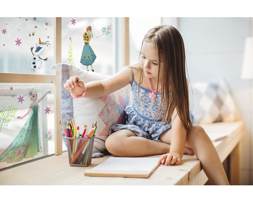 Meisje zit bij het raam met Frozen muurstickers, potloden en papier