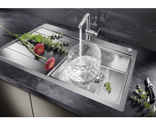 Spoelbak van roestvrij staal met kraan en bloemdecoratie op donker werkblad