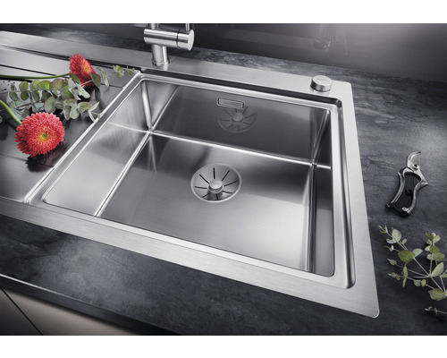 Roestvrijstalen spoelbak met afdruiprek en bloemen op een aanrecht