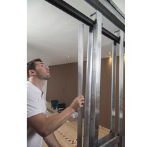 Man monteert een schuifdeurconstructie van metalen profielen in een ruimte.