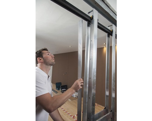 Man monteert een schuifdeurconstructie van metalen profielen in een ruimte.