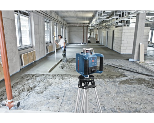 Bosch logo. Bouwplaats met roterende laser op statief voor het nivelleren van de dekvloer.