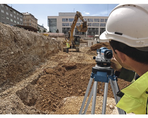 Bouwvakker aan het werk met een waterpasinstrument op een bouwplaats