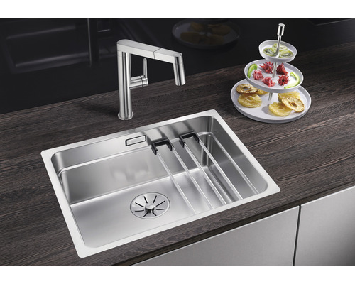 Roestvrijstalen spoelbak met afdruiprek en keukenkraan op een donker werkblad