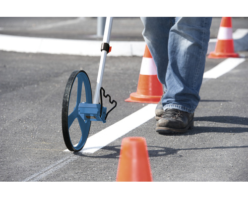 Persoon meet met meetwiel op asfalt