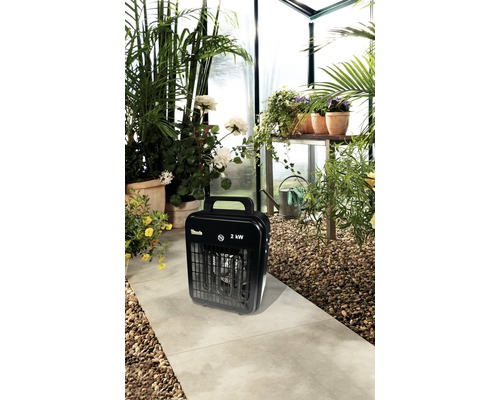 Kas met planten en een zwarte kachel met 2 kilowatt vermogen