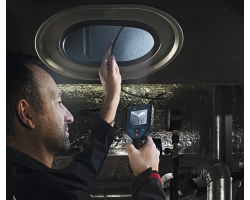 Een man gebruikt een inspectiecamera om een opening te inspecteren.