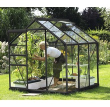Kas met planten en een vrouw in de tuin.