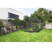 Serre in tuin met planten en tuingereedschap