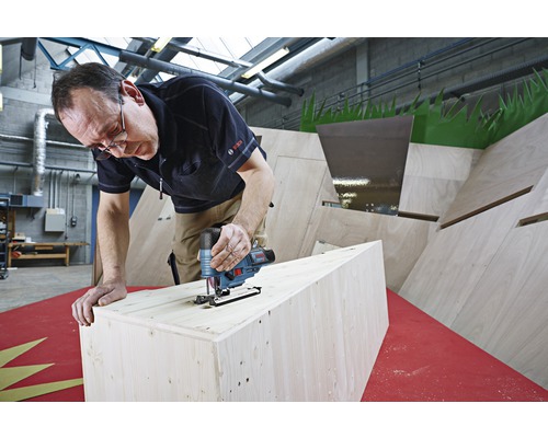 Een man gebruikt een decoupeerzaag om hout te zagen. Het Bosch logo is zichtbaar.