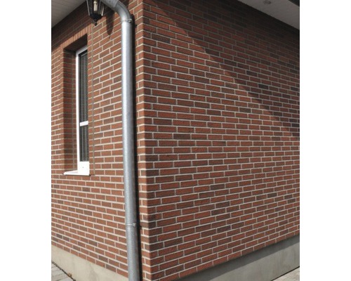 Buitenkant van een huis met bakstenen gevel en regenpijp