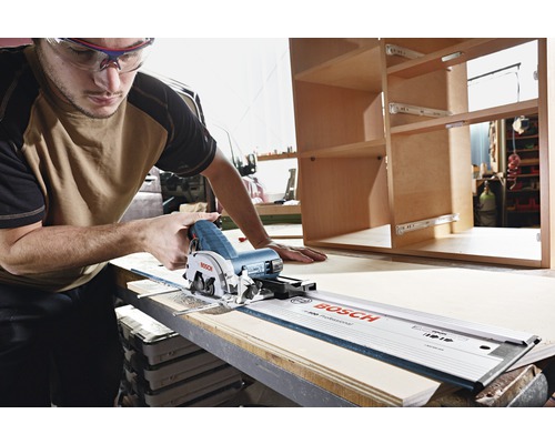 Een man met een veiligheidsbril snijdt hout met een handcirkelzaag en geleiderail van Bosch.