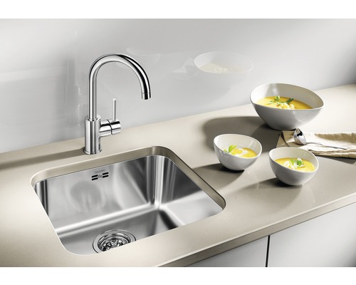 Roestvrijstalen spoelbak met kraan en drie kommen soep op een werkblad