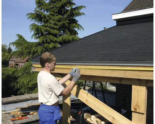 Een man meet een houten constructie met een rolmaat.