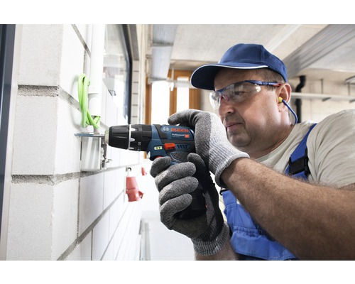 Ambachtsman boort met accuschroefboormachine een gat in een muur