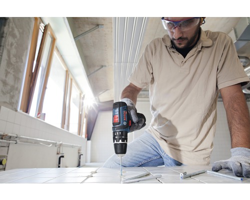 Vakman boort met een accuschroefboormachine een gat in een tegel