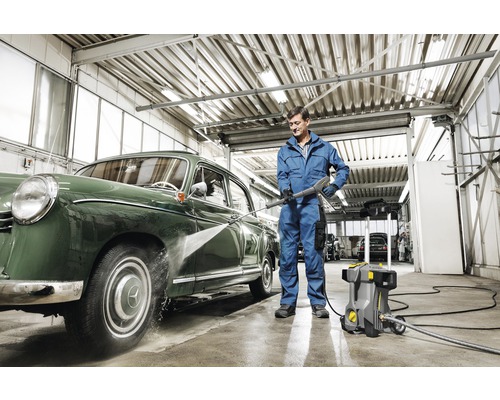 Man reinigt auto met hogedrukreiniger in werkplaats