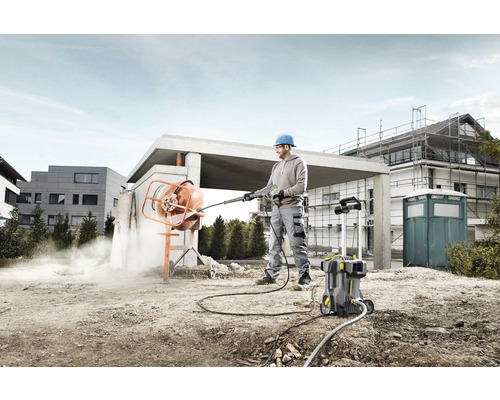 Man reinigt betonmolen met hogedrukreiniger op een bouwplaats.