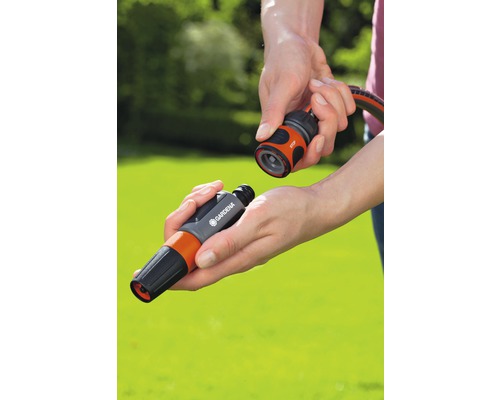 Een persoon verbindt een sproeikop met een slangconnector van Gardena.
