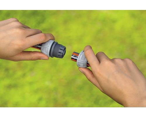 Twee handen verbinden een slangaansluiting met een tuinslang.