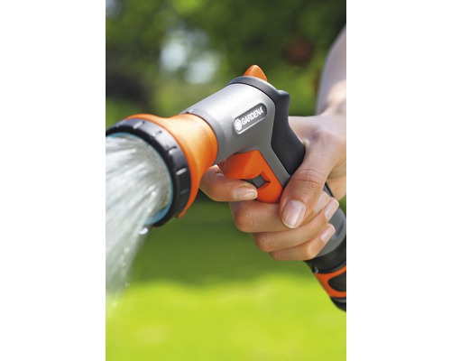 Een hand houdt een tuindouche van Gardena vast waar water uit stroomt.