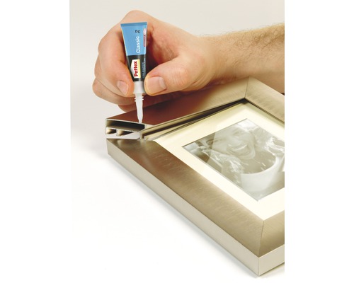 Een hand brengt lijm aan op een fotolijst