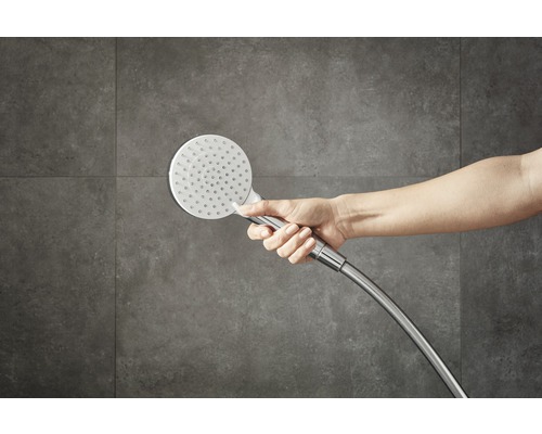 Hand houdt handdouche voor een muur