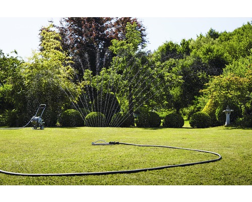 Tuinbesproeiing met gazonsproeier en slangenwagen
