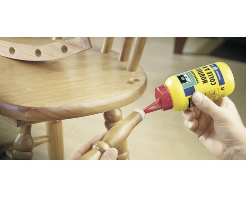 Een persoon lijmt een houten stoel met houtlijm.