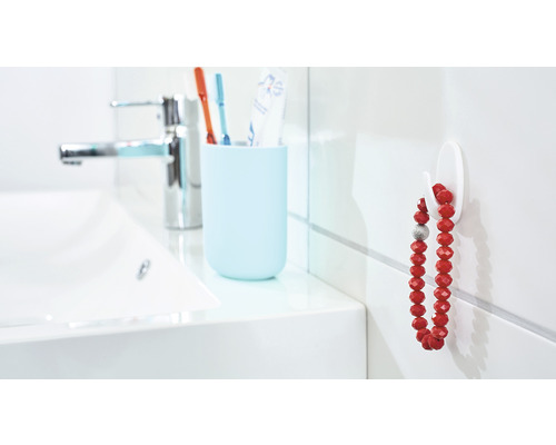 Badkamerwastafel met kraan, tandenborstelbeker en een haak met een ketting