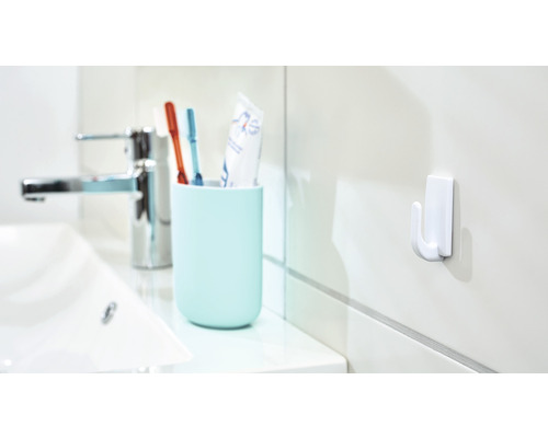 Badkamerscène met wastafel, kraan, tandenborstelbeker met tandenborstels en aan de muur bevestigde haak