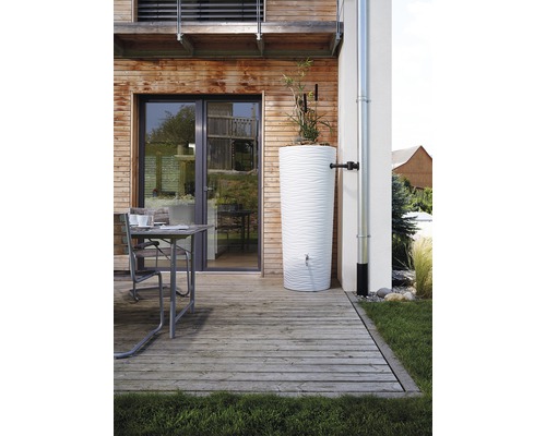 Scene met een witte watercontainer op een houten terras naast een huis.