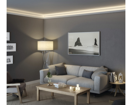 Woonkamer met bank, tafel, staande lamp en indirecte verlichting