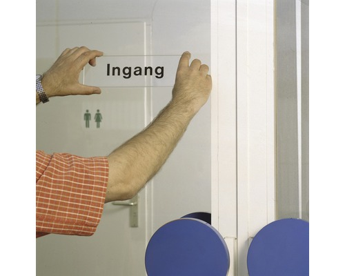 Een persoon bevestigt een bord met het woord ''Ingang'' op een deur.