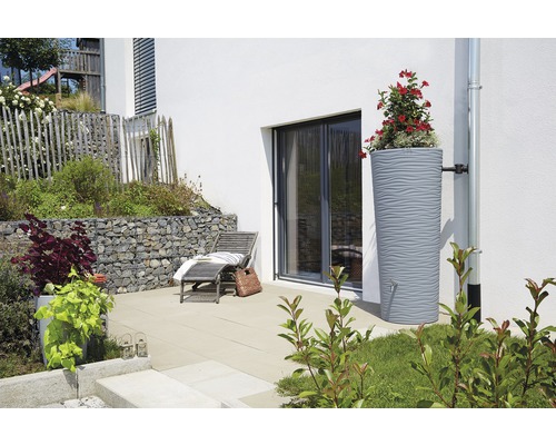 Regenwatertank met beplanting naast een huis met terras en ligstoel