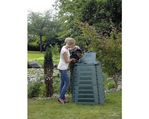 Vrouw vult compostbak met tuinafval in een tuin.