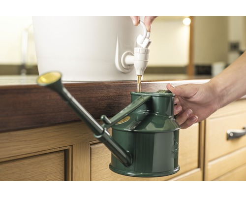 Iemand vult een groene gieter met water uit een kraan.