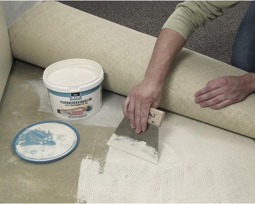 Tapijt leggen met lijm uit een emmer en een plamuurmes