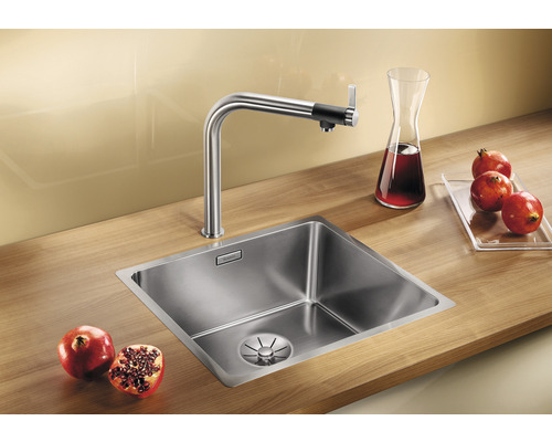 Roestvrijstalen spoelbak met kraan en granaatappels op een houten werkblad.