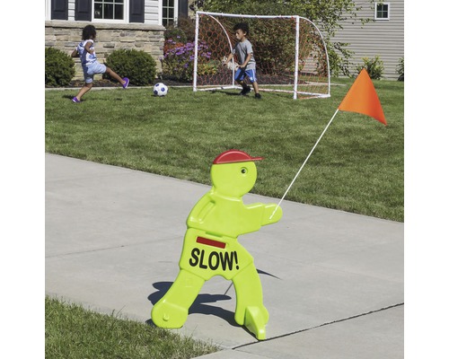 Kinderveiligheidsschild met het opschrift ''Langzaam!'', met kinderen die op de achtergrond voetballen
