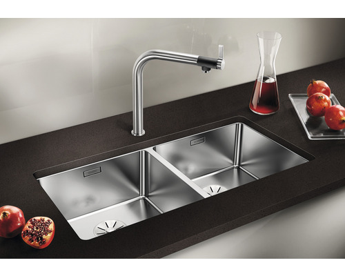 Dubbele spoelbak van roestvrij staal met kraan op een donker aanrecht