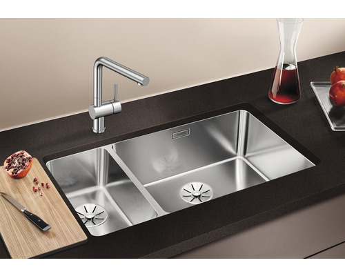 Dubbele spoelbak van roestvrij staal met kraan op een donker werkblad