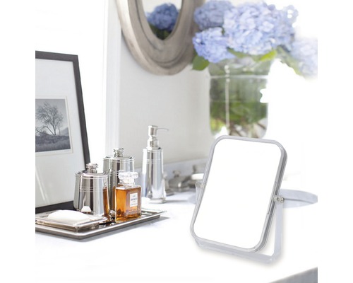 Badkameropstelling met make-upspiegel, zeepdispenser en decoratieve items op een wit oppervlak