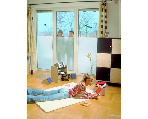 Woonkamer met raamfolie voor meer privacy, een vrouw ligt op de grond te lezen.