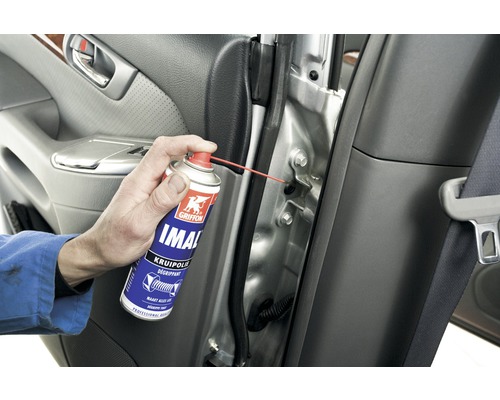 Een persoon spuit smeerolie op een autodeurscharnier.