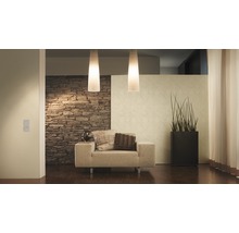Woonkamer met fauteuil, staande lamp, kamerplant en stenen muur