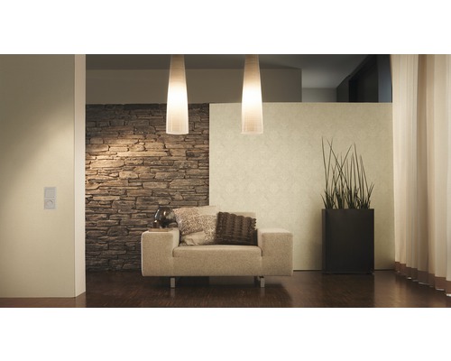 Woonkamer met fauteuil, staande lamp, kamerplant en stenen muur