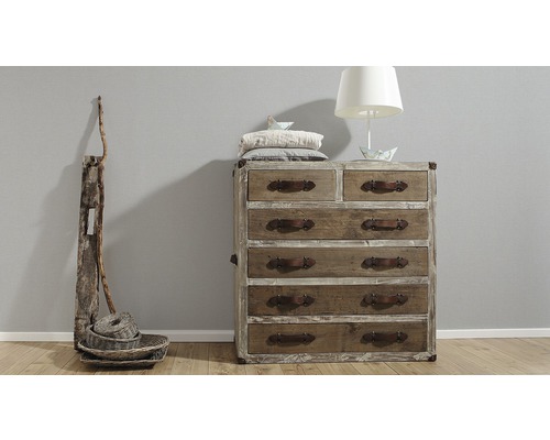 Ladekast met meerdere laden en lederen handgrepen, samen met een vloerlamp en decoratieve manden