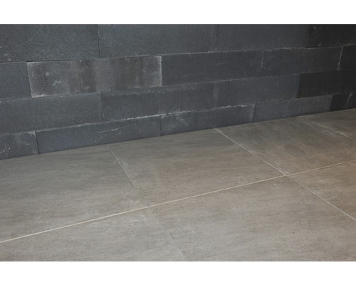 Wandbekleding van donkere steen en vloertegels.