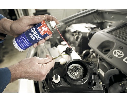 Een spuitbus contactspray wordt op een autokoplampcontact gespoten.